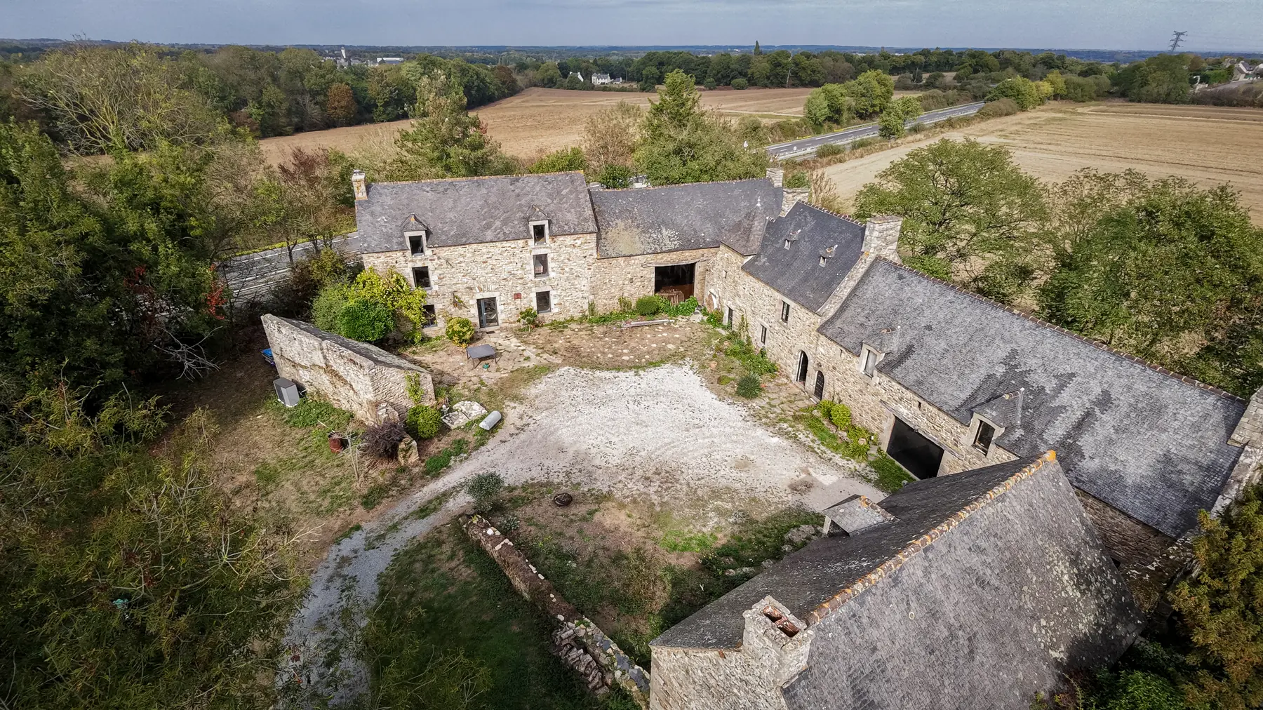 Vue de drone d'une longère en pierre et de sa cour, en Bretagne